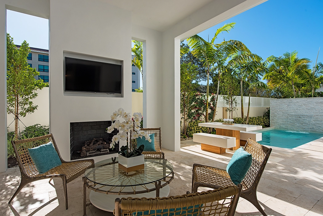 Patio with TV over the fireplace and pool with waterfall feature